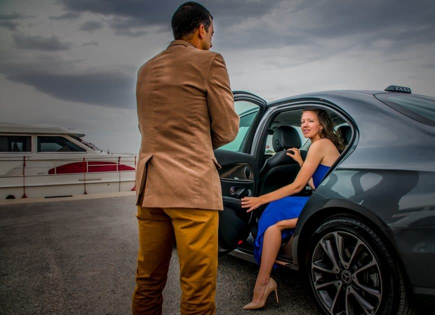 Professional driver of Crete Taxi Transfers helping a lady of or a Mercedes luxury taxi.